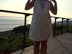 Rijpe vrouw in witte jurk heeft buitenseks op het balkon