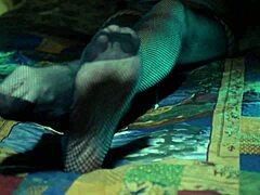 Wanita dewasa memamerkan jari kakinya dalam stoking fishnet yang seksi
